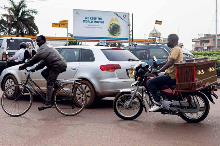 A boda boda man carries a coffin in a busy street. © Badru Katumba