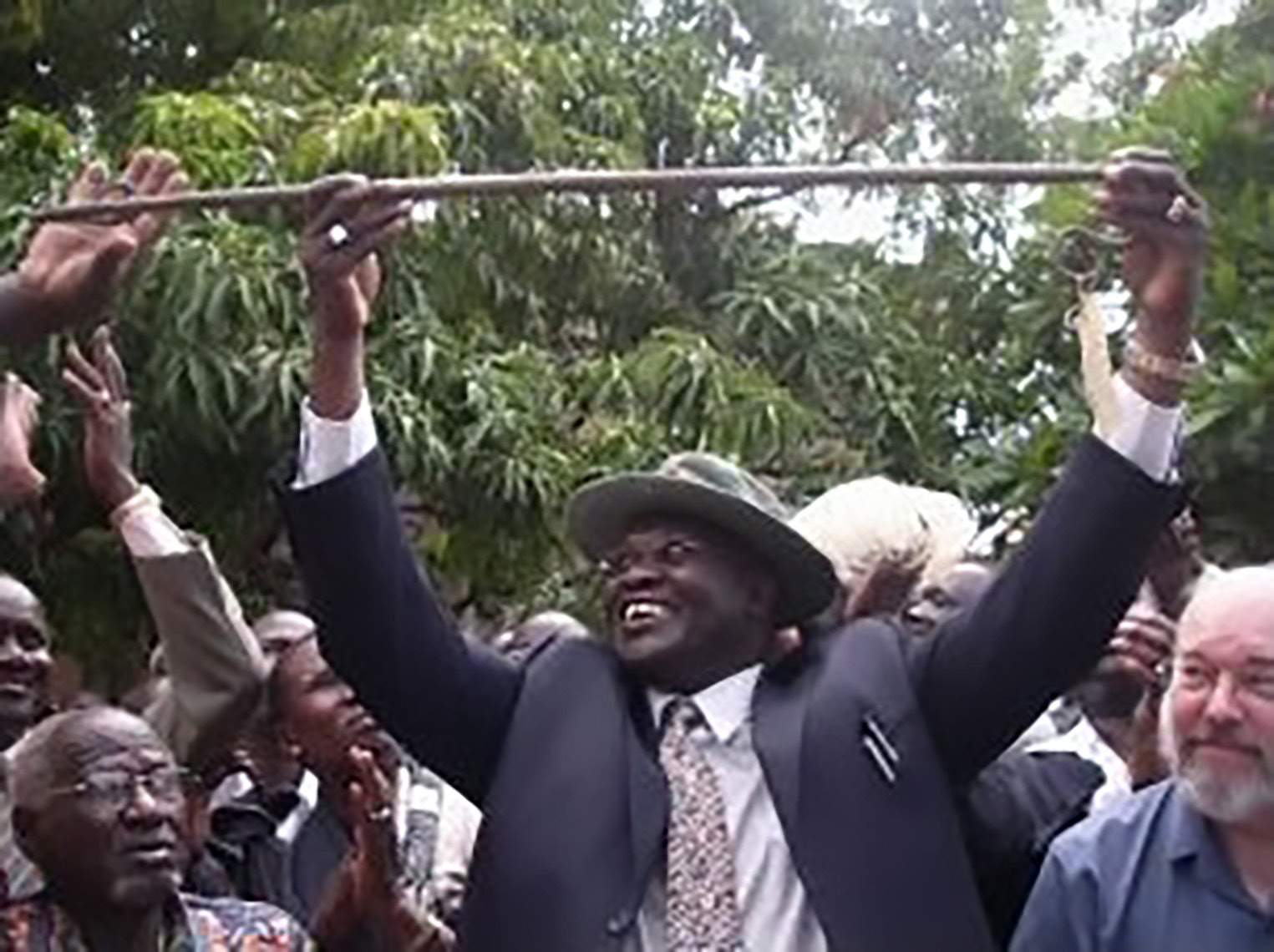 9. Photo of a Man Raising a Stick Amid a Cheering Crowd The Weganda Review Issue 13 Riek Machar with Ngundeng’s dang in May 2009. (Courtesy of the Sudan Tribune)